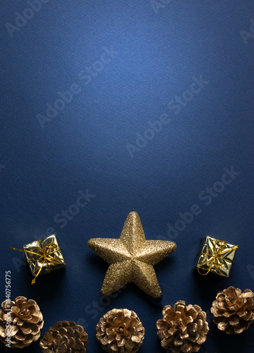 Christmas minimalistic vertical dark blue background with glittering stars, golden gift boxes and pine cones for tree decoraton. New Year winter holiday composition and space for text, top view.