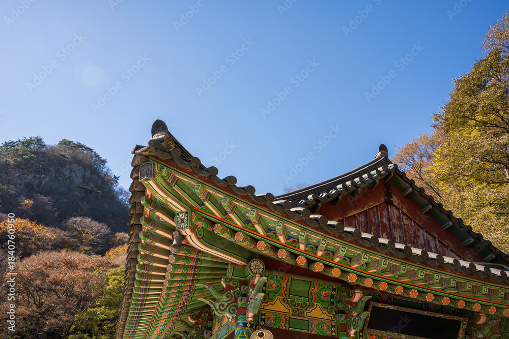 Naklejka premium Traditional Korean Temple Eaves with Colorful Dancheong Patterns Under Clear Autumn Sky