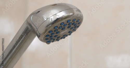 Turning on the water in shower. Water flows out of the shower head. Shower head in bathroom