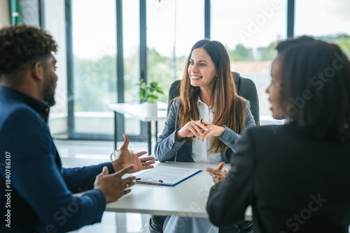 Photos Businesswoman discussing contract with diverse business partners in office