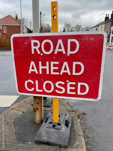 Red caution signage warns of road ahead being closed to traffic