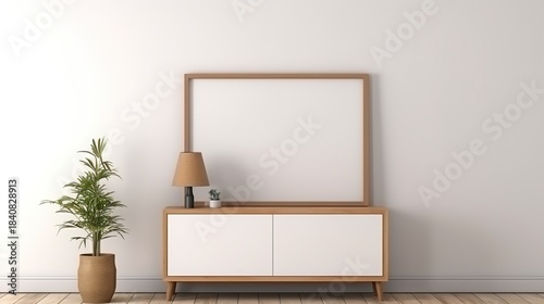 Wallpaper Mural A minimalist interior scene featuring a wooden framed blank picture frame on top of a white sideboard with a small plant and lamp Torontodigital.ca