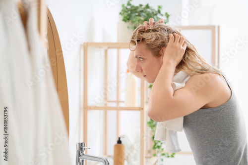 Young blonde man washing ha...