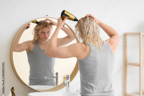 Young blonde man drying wet...