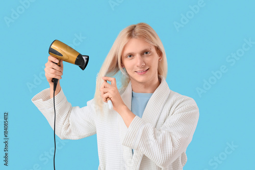 Young blonde man drying hai...