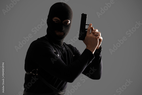 Obraz na płótnie Male robber in balaclava with gun on grey background