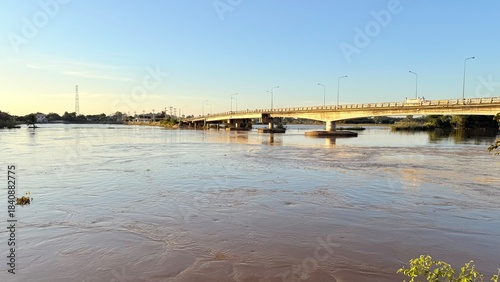 High angle view of strong muddy water current flowing fast around concrete bridge pillar, flood disaster concept.