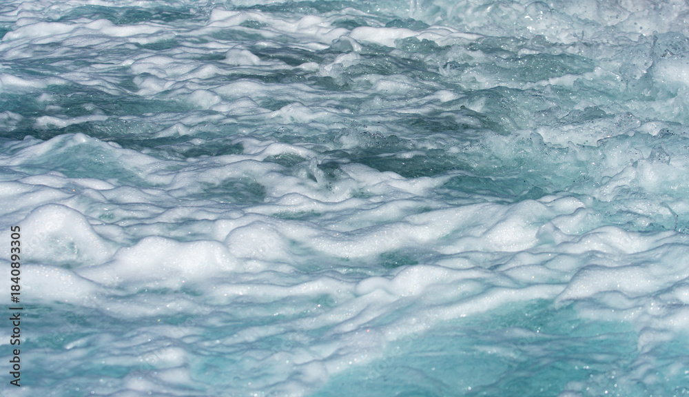 Obraz premium Waves ocean texture. Ocean waves move. Foamy sea wave with oceanic power. Sea waves in tropical sunshine. Crystal wave reflect light. Sea waves curl and break on the coast.