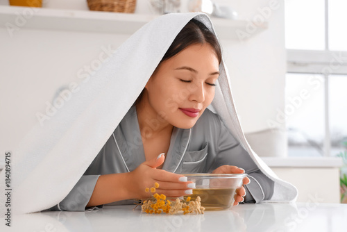 Εκτύπωση καμβά Young Asian woman doing steam inhalation at table in kitchen