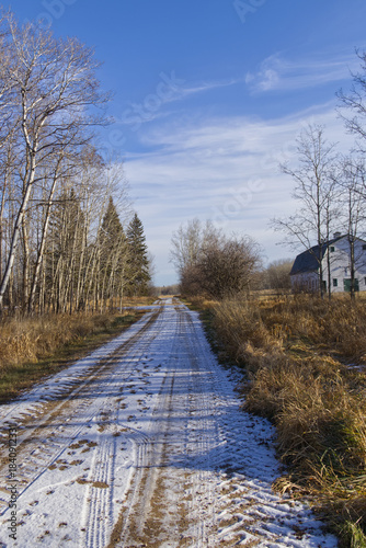 Snow on a dirt road with a Barn at the side