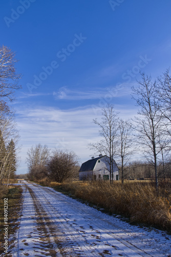Snow on a dirt road with a Barn at the side