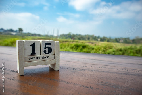 Wooden cube calendar for 15th September place on a table in a sunny day background	