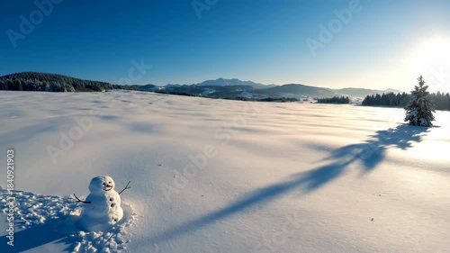 A cheerful snowman stands in a vast snowy landscape under a bright blue sky.