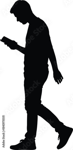 Silhouette of a young man walking while using a mobile device