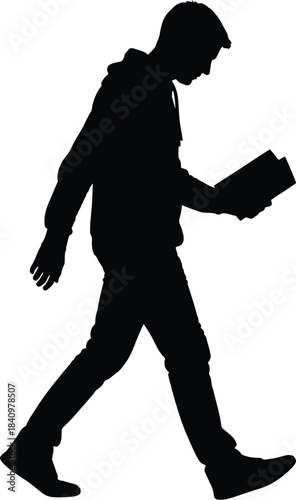 Silhouette of a young man walking while reading a book