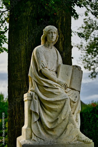 sitzende Frau auf einem Gedenkstein mit einem Buch in der Hand  Friedhof in Goch