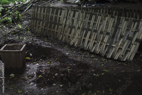 Rustic Garden Corner with Bamboo Fence and Empty Planter on Muddy Ground