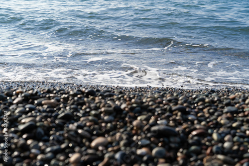 Indulge in a tranquil day at a luxurious spa retreat. The setting features smooth pebbles lining the shore and gentle waves lapping against the coast, creating a peaceful environment.
