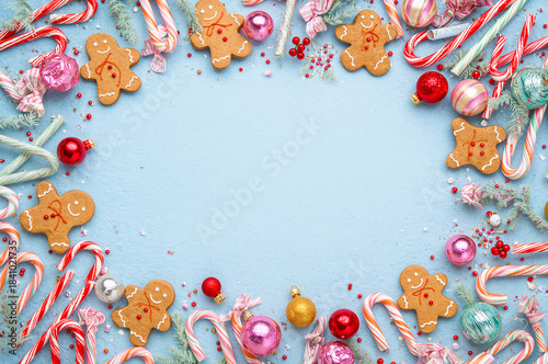 heerful and colorful Christmas, Holiday flat lay featuring gingerbread men and candy canes on a light blue background, surrounding a central blank area. copy space