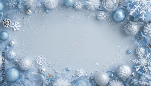 Icy blue and silver winter-themed flat lay with sparkling ornaments, snowflakes, glitter, and feathery accents surrounding a cool blue central area. copy space