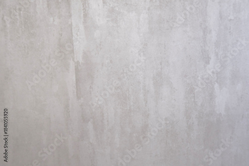 white concrete wall with a subtle, distressed, and aged look. The surface is textured with a blend of light grey and white tones, creating a calming and minimalist backdrop.
