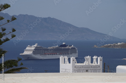Luxury modern Italian cruiseship cruise ship liner Magnifica at sea anchoring in front of Mykonos Island in summer during Mediterranean Aegean Greek Island cruising dream vacation