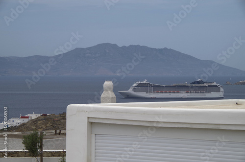 Luxury modern Italian cruiseship cruise ship liner Magnifica at sea anchoring in front of Mykonos Island in summer during Mediterranean Aegean Greek Island cruising dream vacation