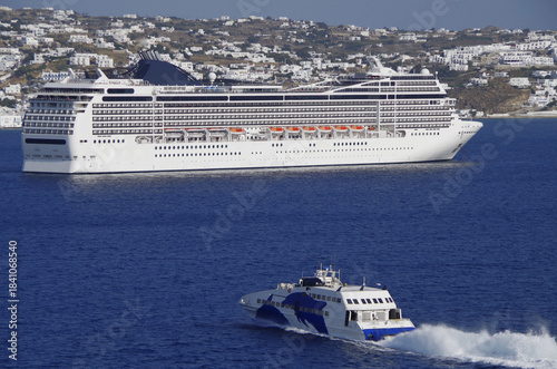 Luxury modern Italian cruiseship cruise ship liner Magnifica at sea anchoring in front of Mykonos Island in summer during Mediterranean Aegean Greek Island cruising dream vacation