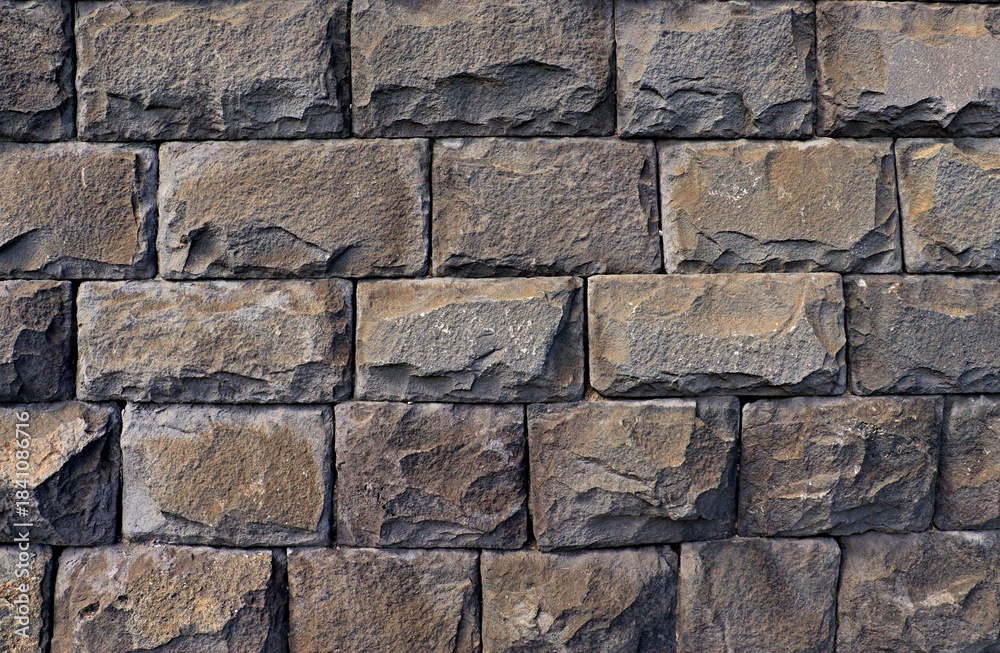 Fototapeta premium Background, texture wall composed of natural stone volcanic tuff gray, roughly processed