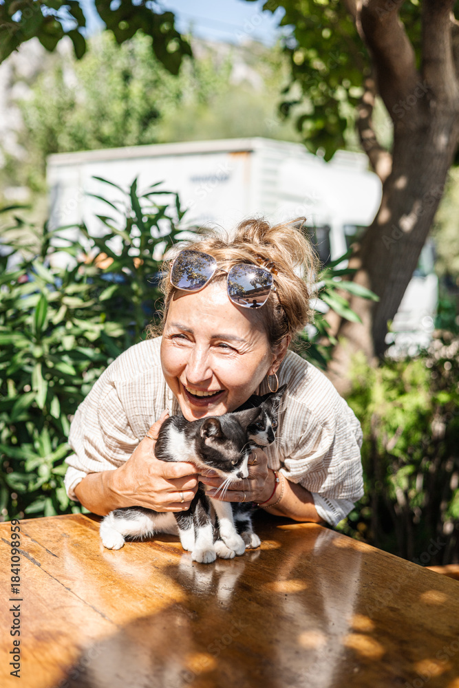 Naklejka premium middle-aged woman holds a small black and white cat in her arms