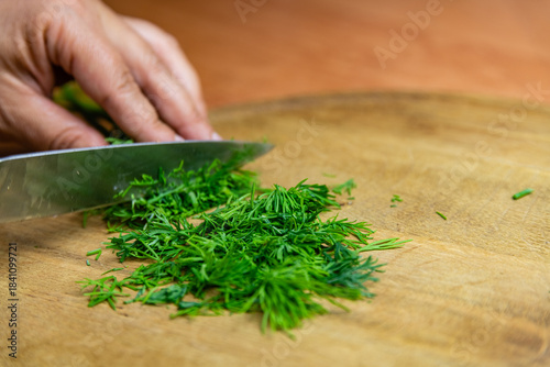 Woman cutting green dill on the cutting board