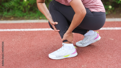 Tableau sur toile Woman runner holding leg suffering from muscle and tendon sprain pain in ankle at outdoor stadium, close-up