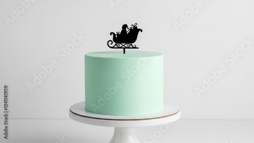 Modern mint green Christmas cake with black sleigh silhouette topper on white stand, minimalist elegant holiday dessert design for chic winter celebrations and stylish festive photo shoots

