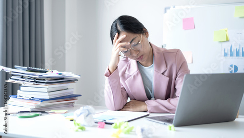 Working Asian women feel stressed, tired from work, migraine headaches from hard work while working at the office