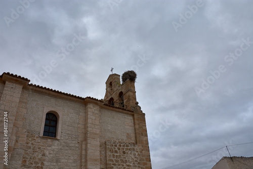 Stone bell tower with a cross and stork's nest at the Church of Saint Martin of Tours in Banos de Cerrato