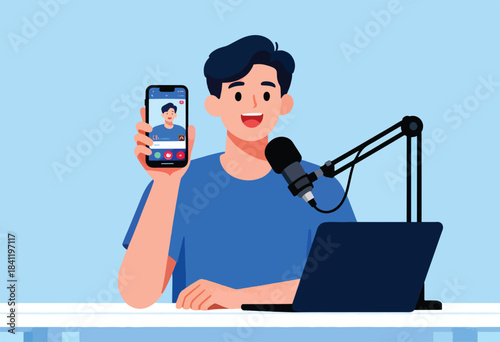 A smiling man holds a phone showing a video call while behind a microphone and laptop, on a blue background