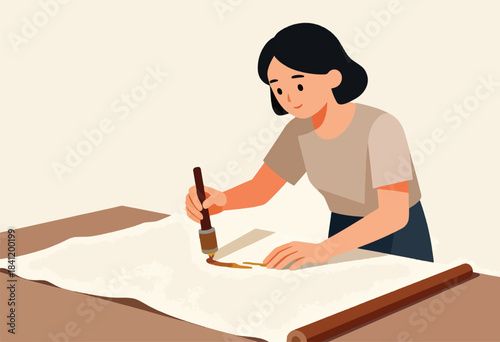A woman in a light-colored shirt paints with a brush on a large paper canvas laid flat on a table