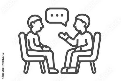 Two people engage in a conversation while seated in chairs during a discussion in a neutral setting