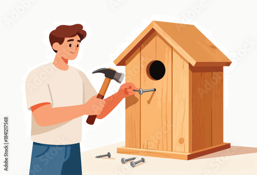 A person, using a hammer, nails a nail into a wooden birdhouse. Several nails lay nearby
