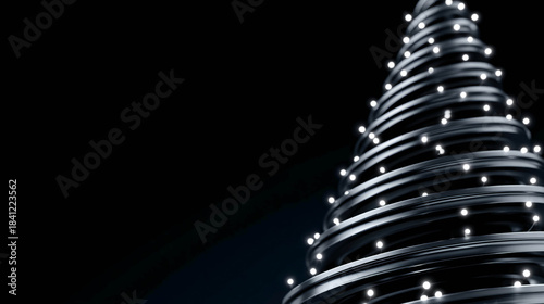 An abstract Christmas tree made of metal spirals with white lights on a black background.
