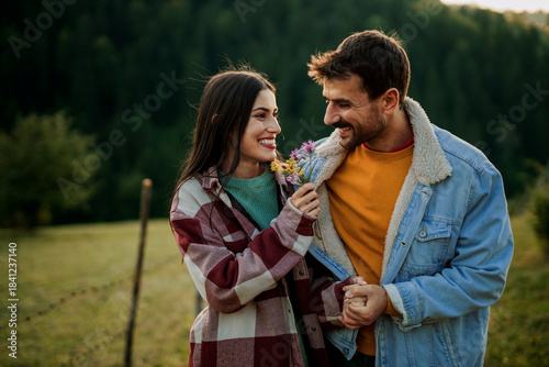 Romantic couple enjoying outdoor date presenting flowers