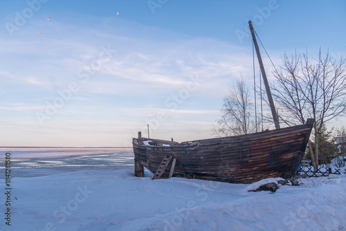 Old wooden fishing boats beached in winter near Petrozavodsk, from time of historic Karelian sailors and northern explorers of Lake Onega routes.
