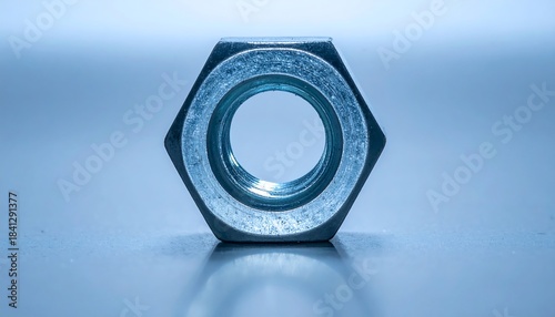 青い照明の中でステンレス六角ナットが中央に置かれた静物構図