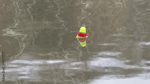 A fishing float is on the water's surface in a river on a cloudy day