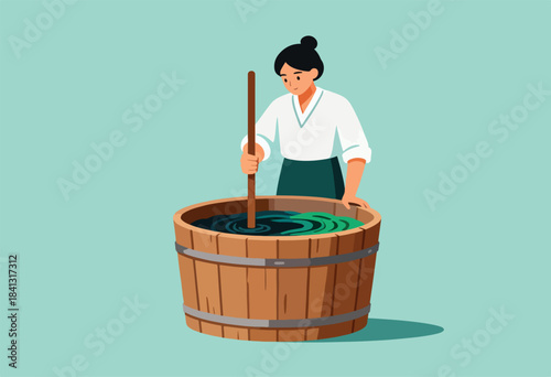 Person stirring liquid in wooden vat