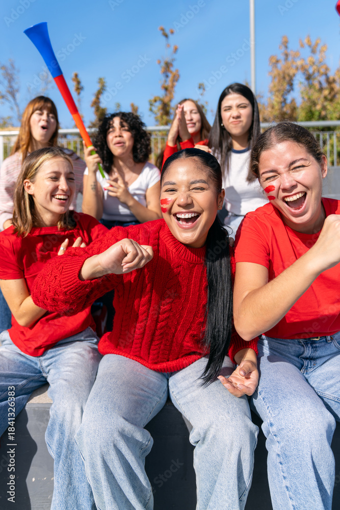 Fototapeta premium Multiethnic women friends cheering enthusiastically, supporting their team at a vibrant stadium sport event