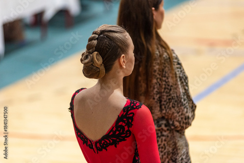 A woman with her back turned is wearing a red dance dress accented with black lace. 
