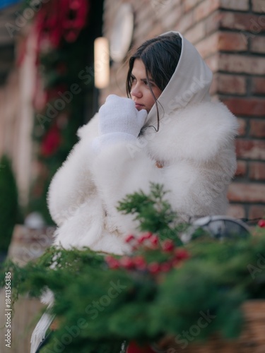 Thoughtful Woman in White Mittens and fur coat against Christmas Decor, Close-Up