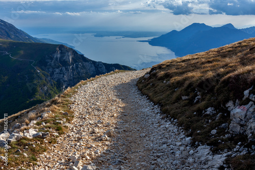 Photography Rocky trail toward Monte Altissimo summit with panoramic view of Lake Garda and surrounding mountains