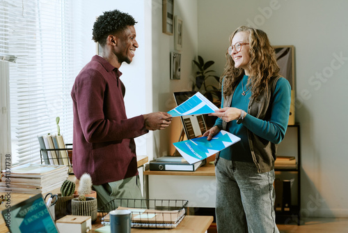 Tableau sur toile Caucasian young adult woman and Black young adult man standing in office exchang